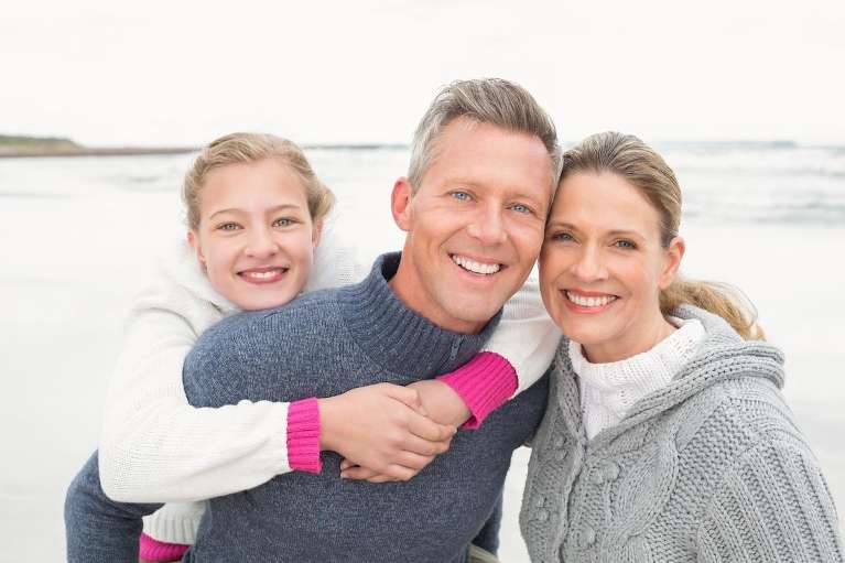 A family on the beach smiling after a Comprehensive Family Dentistry treatment in Clayton, NC