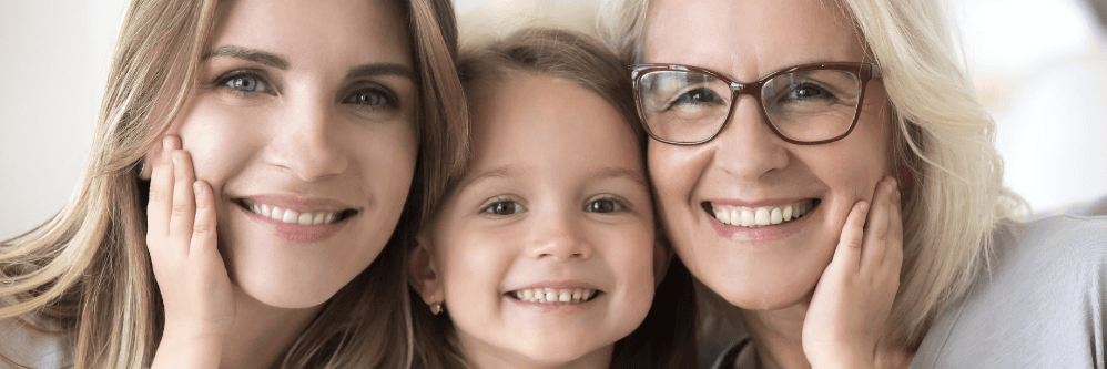 A smiling mother, daughter, and grandmother, radiating happiness and love