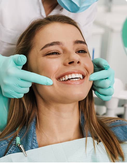 Clayton Smiles | Dental patient smiling as a dentist gently checks her teeth during an exam